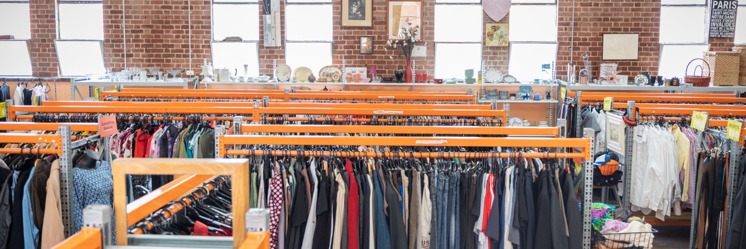 The inside view of the BSL Burnley op shop. The shop is inside a large brick-walled building with high roofs and big windows. 