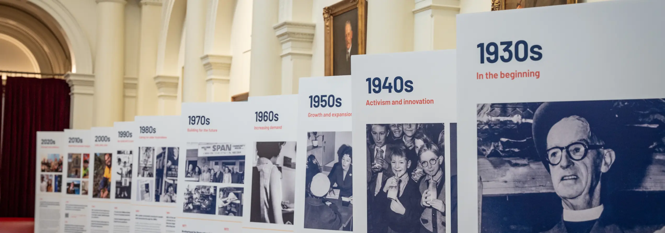 An array of stands at the BSL expo, each with a poster on it which shows one era from the BSL timeline.
